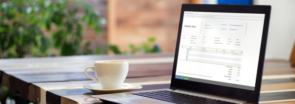 Photo of an invoice on a laptop screen with a cup of coffee on the table