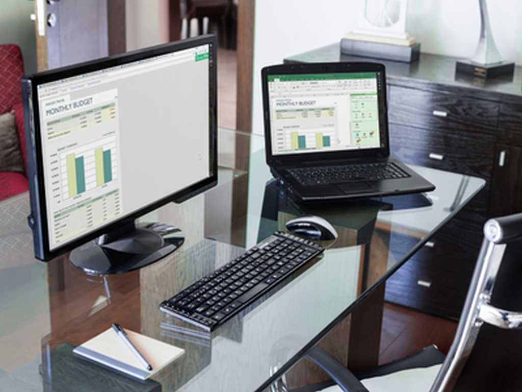Photo of a laptop with a form developed in Excel and a desktop with the same form as a web page in Google Chrome